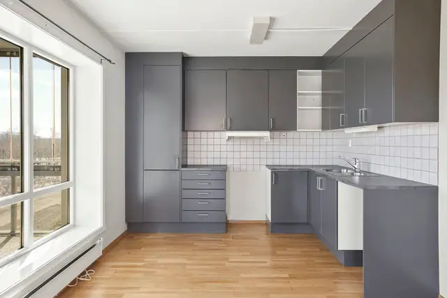 Kjøkkenet har glatte fronter  i en dempet farge og benkeplate av laminat. Det er godt med skapplass.