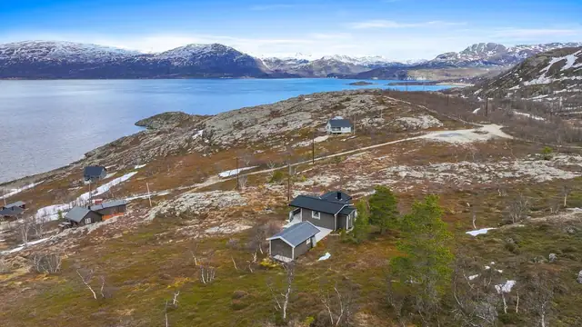 Oversiktsbilde som viser hyttas plassering i det storslåtte landskapet.